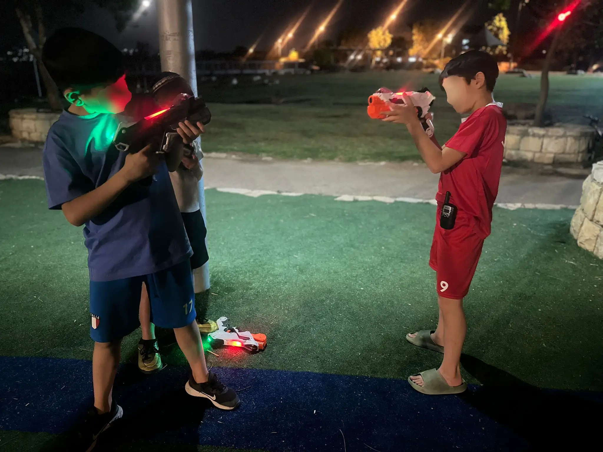 שני שחקנים מכוונים רובי לייזר מוארים על דשא בלילה